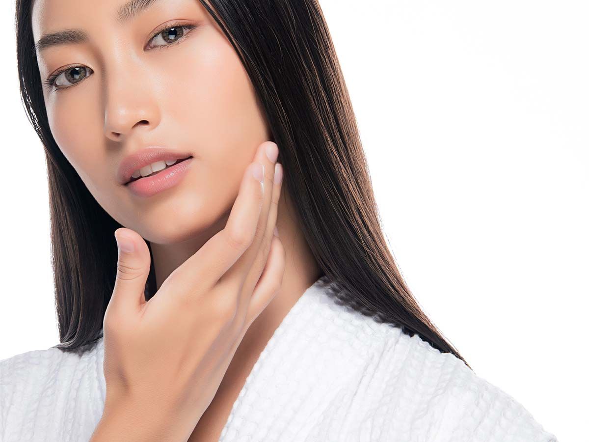 Woman with healthy skin touching her face.
