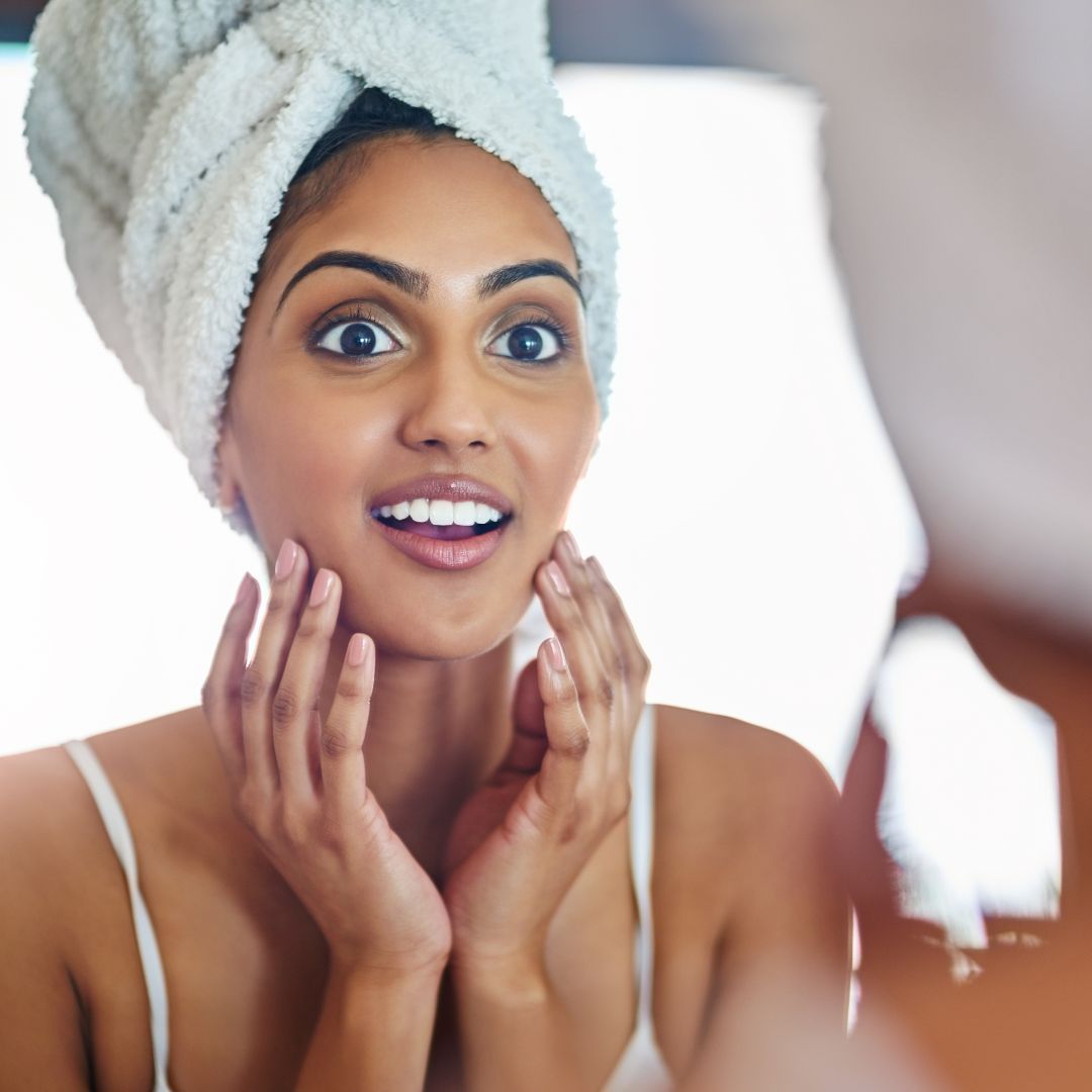 Surprised woman admiring her reflection in mirror.