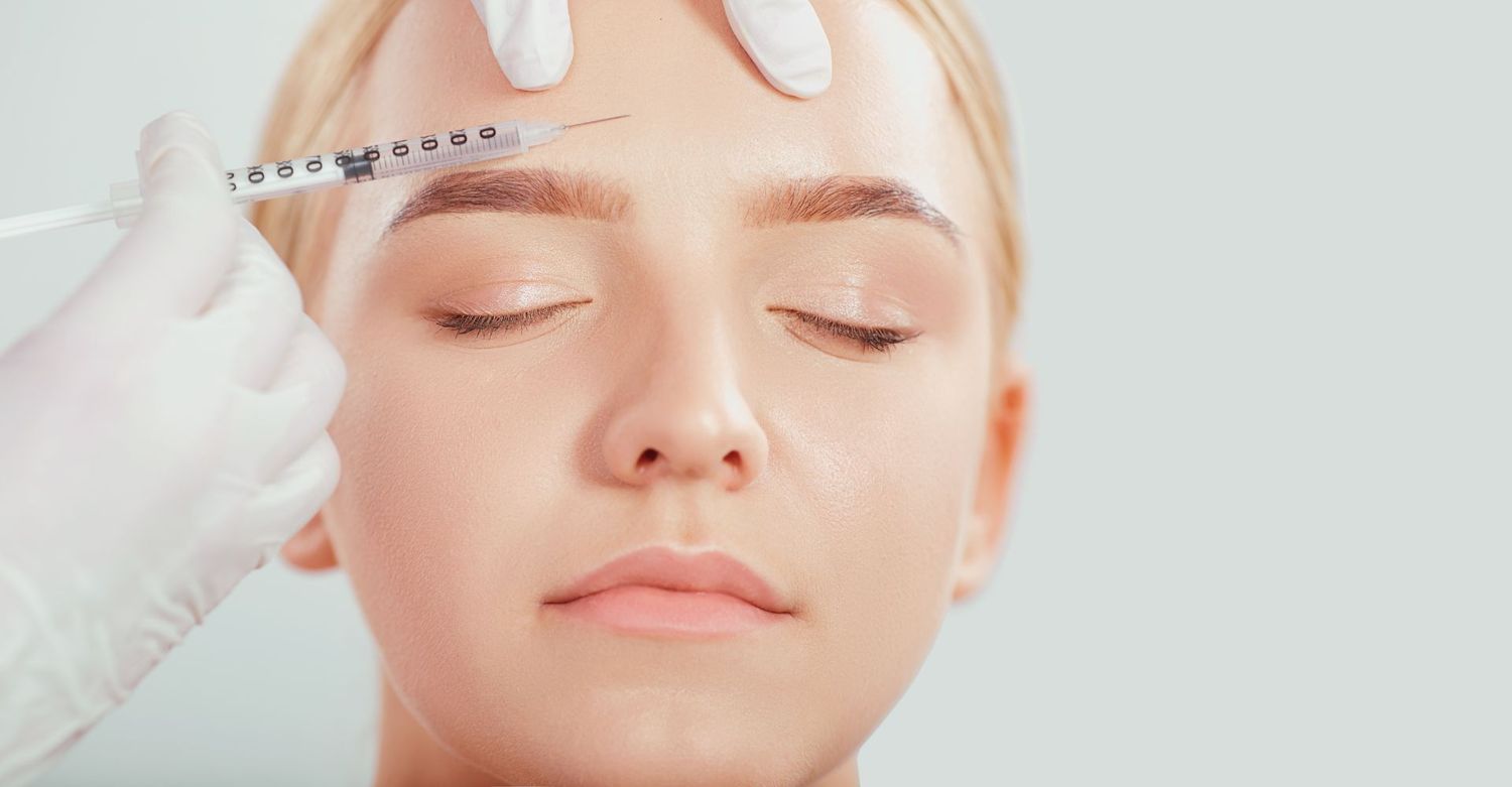 Injecting cosmetic treatment on a woman's forehead.