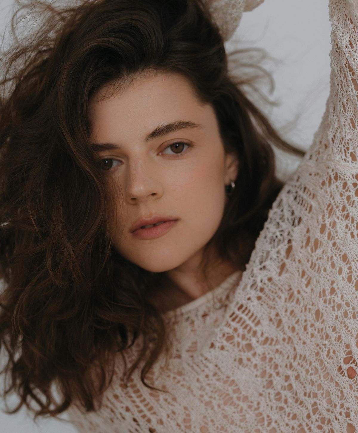 Woman with wavy hair in lace sweater.