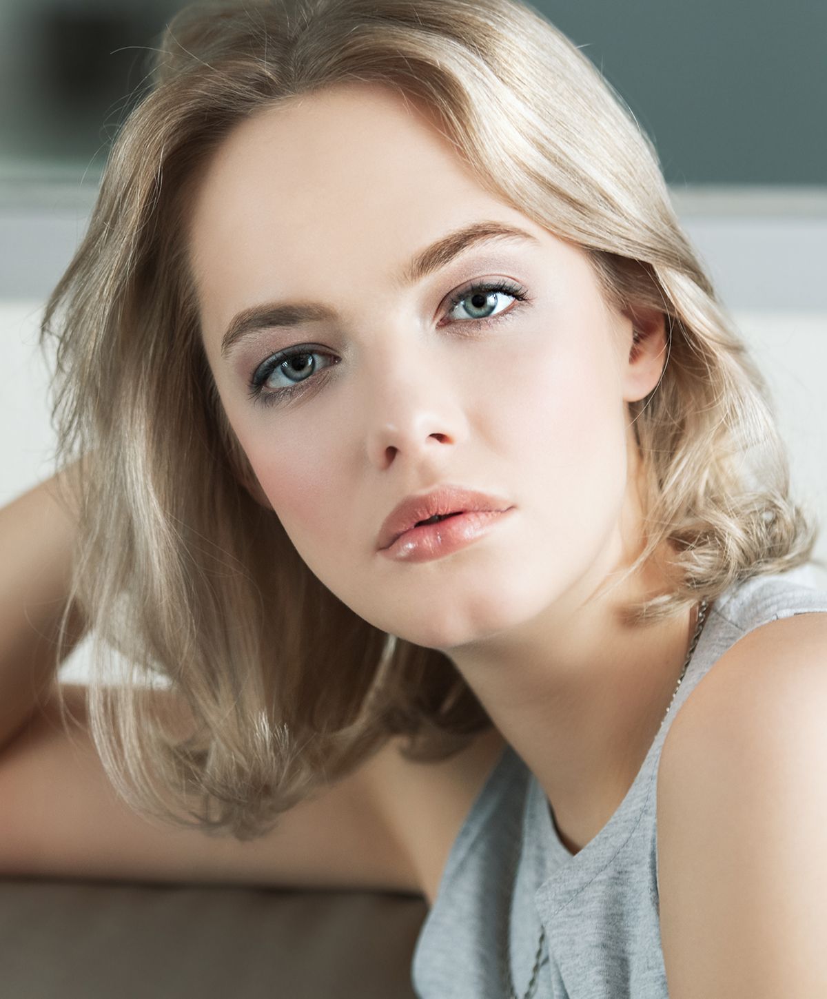 Blonde woman with soft makeup, relaxed pose.