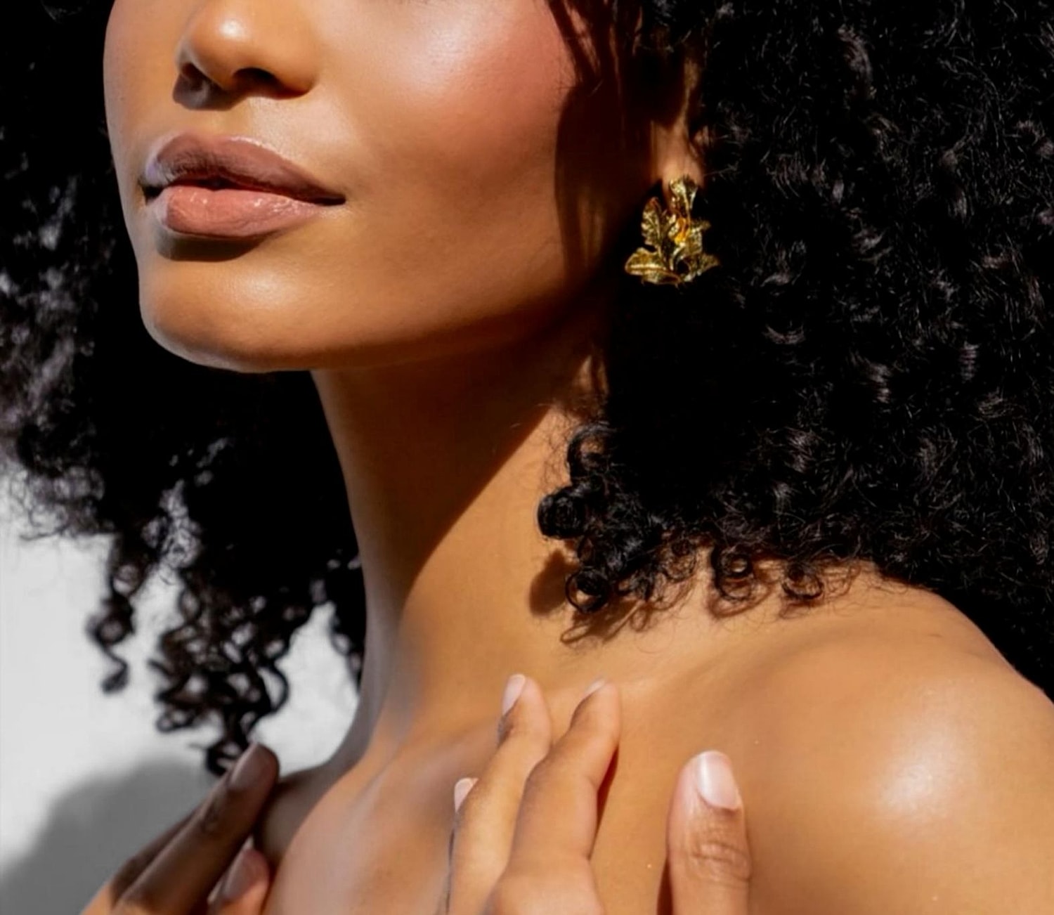 Woman with curly hair and gold earrings.