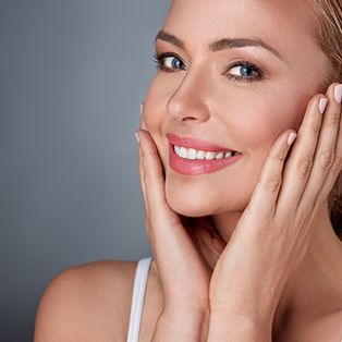 Smiling woman touching her face, glowing skin.