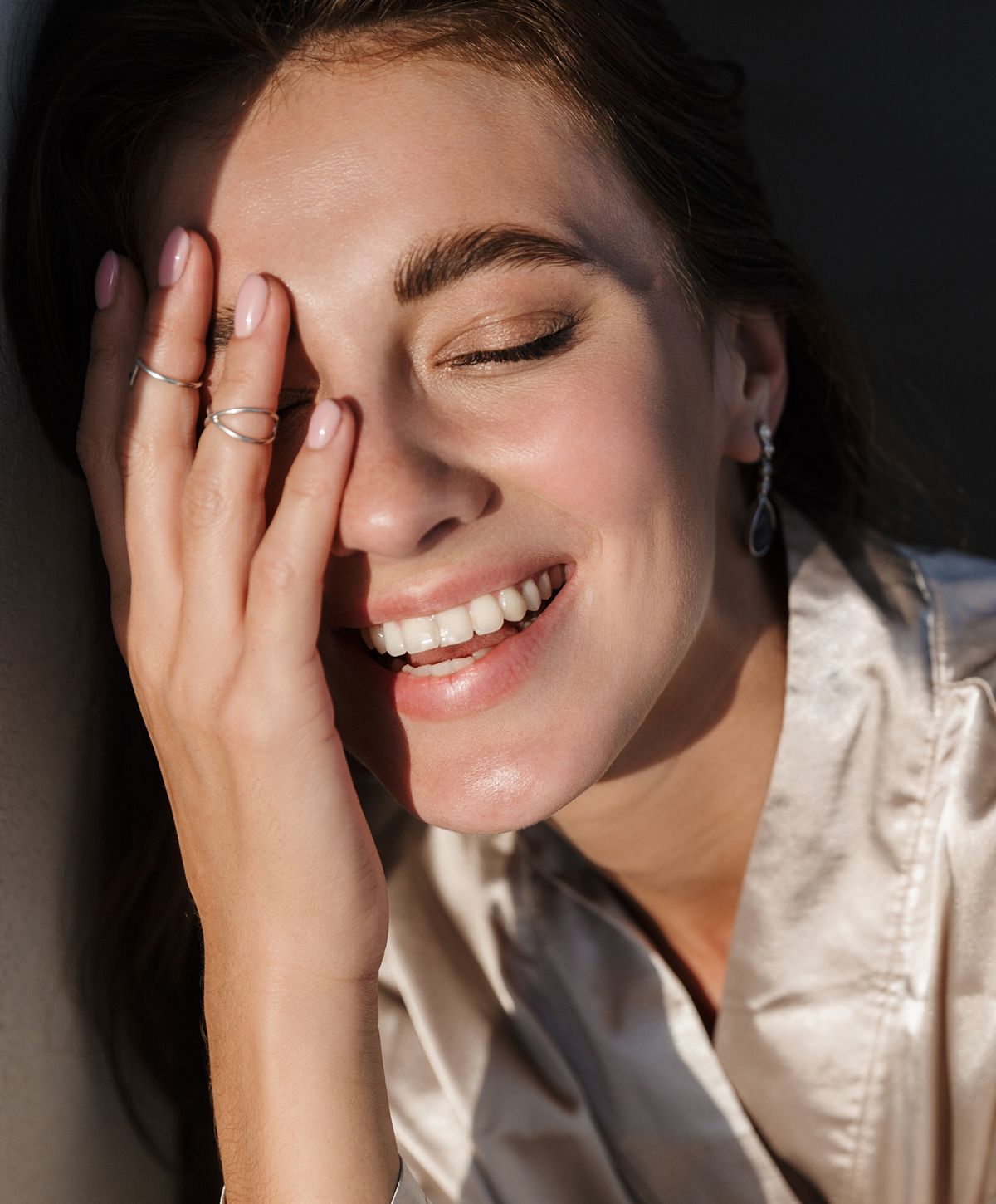 Smiling woman with hand covering half her face.