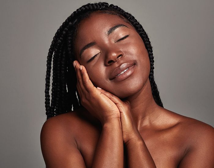Smiling woman with braided hair, serene expression.