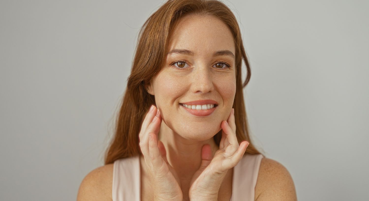 Smiling woman touching her face gently.